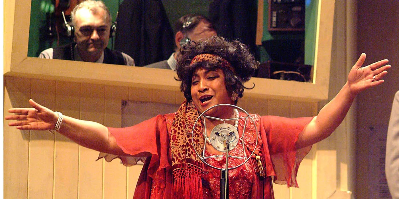 A woman singing into a spring-suspended retro style standing microphone.